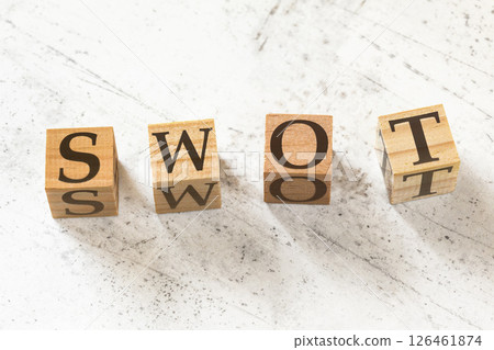 Four wooden cubes with letters SWOT (meaning Strength, Weakness, Opportunity, and Threat Analysis) on white working board. 126461874
