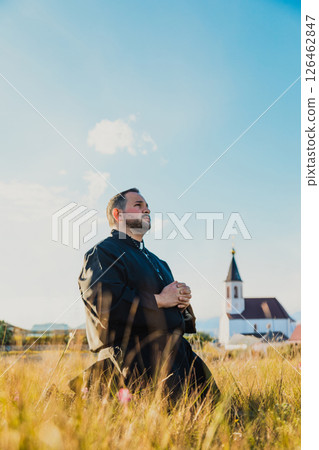 Monk Praying In The Nature With A Church In The Distance Monk Praying In The Nature With A Church In The Distance 126462847