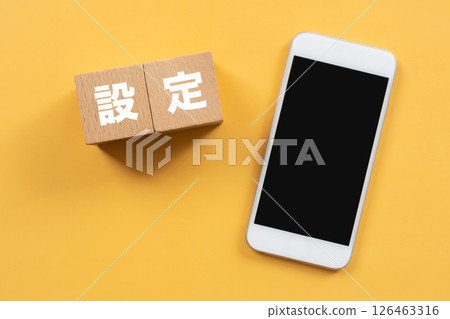 A block with the word "settings" written on it and a smartphone 126463316