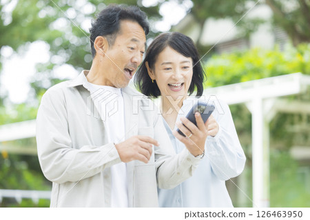 Senior couple looking at a smartphone outdoors Senior couple looking at a smartphone outdoors 126463950