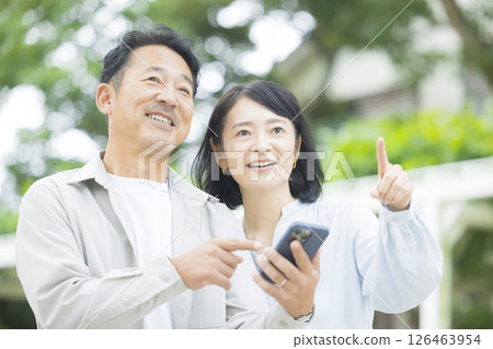 Senior couple looking at a smartphone outdoors 126463954