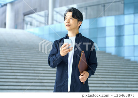 在辦公室操作智能手機的商務休閒男工程師 在辦公室操作智能手機的商務休閒男工程師 126463975