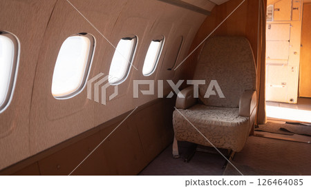 Interior view of a vintage USSR aircraft highlights a plush seat next to several windows, showcasing the unique design elements from the Soviet era of aviation. 126464085