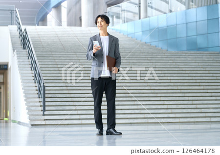 Business casual male engineer operating a smartphone in the office Business casual male engineer operating a smartphone in the office 126464178