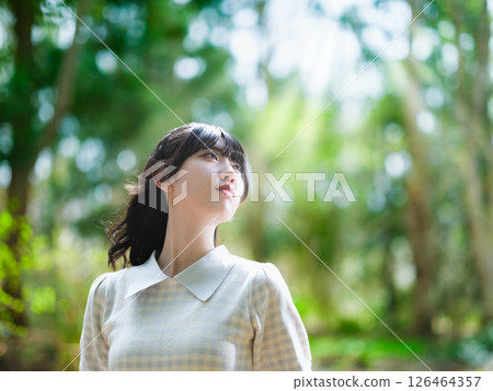 A woman strolling through a forest filled with sunlight filtering through the trees 126464357