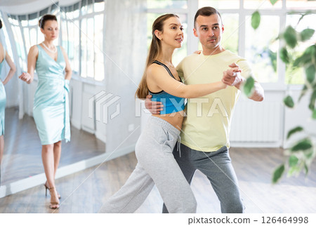 Couple in comfortable sports clothes waltz dancing during individual lesson Couple in comfortable sports clothes waltz dancing during individual lesson 126464998