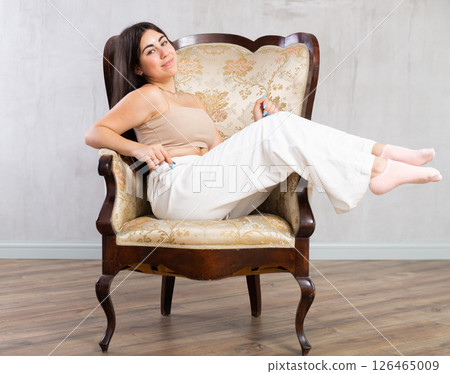 Young woman sitting in attractive pose on retro-style armchair Young woman sitting in attractive pose on retro-style armchair 126465009