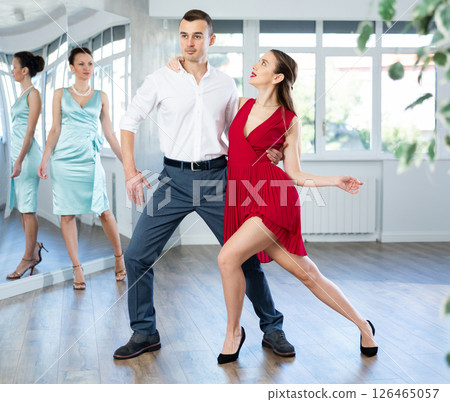 Couple in stage costumes learns tango dancing during individual lesson 126465057