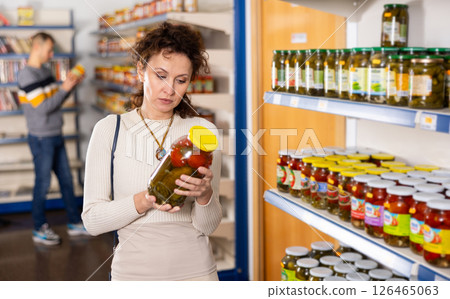 Adult woman chooses pickled cucumbers and tomatoes 126465063
