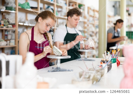 Teenage girl painting ceramic cup in ceramic workshop Teenage girl painting ceramic cup in ceramic workshop 126465081
