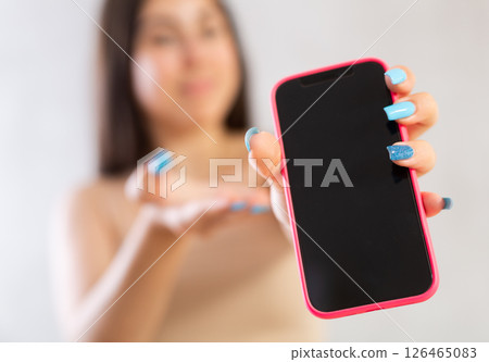 Mobile phone held in hand against blurred background Mobile phone held in hand against blurred background 126465083