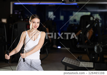 Active athlete young woman during exercises on crossover exercise machine with loops and weighting 126465108