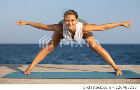 On windy day young slender woman does yoga near sea doing Himavanasana On windy day young slender woman does yoga near sea doing Himavanasana 126465218