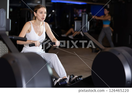 Sportive young girl training on cable row machine in gym Sportive young girl training on cable row machine in gym 126465220