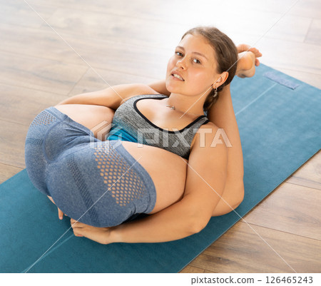 Lover of active lifestyle on yoga mat perform doing yoganidrasan in gym Lover of active lifestyle on yoga mat perform doing yoganidrasan in gym 126465243