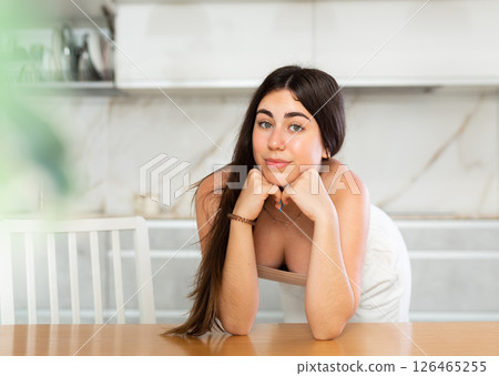 Smiling young woman posing leaning on kitchen table 126465255