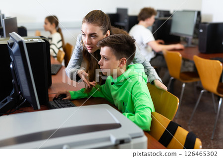 Female teacher consulting tween boy studying in computer class Female teacher consulting tween boy studying in computer class 126465302