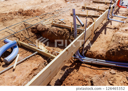 Workers set up plumbing foundation forms on construction site during works day preparing for new structure. 126465352