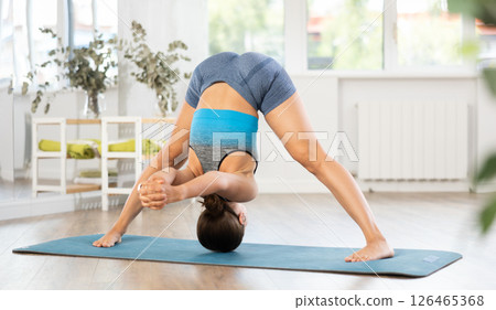 Young woman practicing yoga asanas on mat in youga studio Young woman practicing yoga asanas on mat in youga studio 126465368