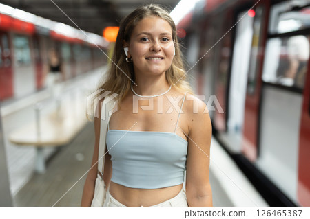 Young woman with headphones standing at metro station 126465387
