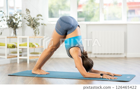Lover of active lifestyle on yoga mat perform doing Adho Mukha Svanasana in gym 126465422