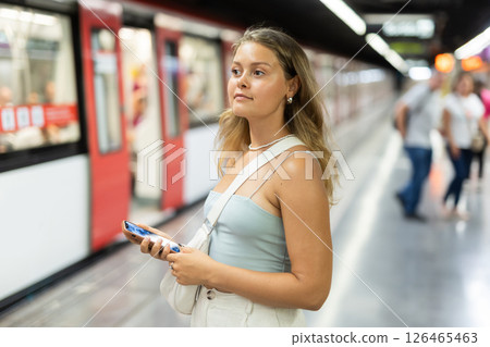 Young woman with phone stands at metro station Young woman with phone stands at metro station 126465463