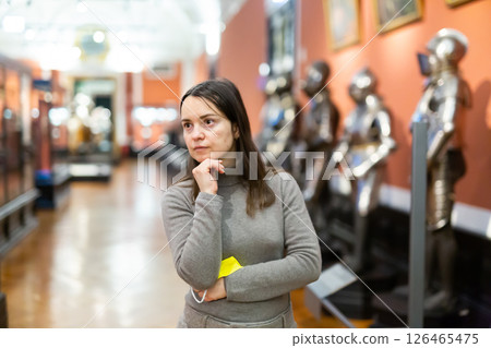 Interested woman viewing collection of medieval armor in museum Interested woman viewing collection of medieval armor in museum 126465475