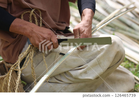 A man cutting bamboo to the same length 126465739