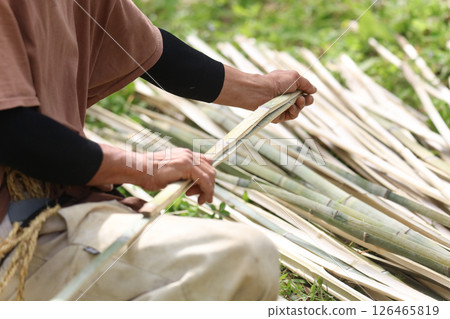 A man cutting bamboo to the same length 126465819