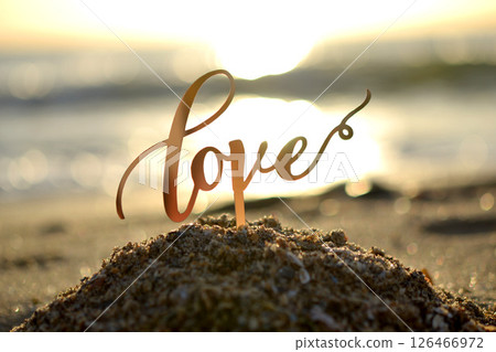 Outlines of word Love at dawn and sunset on background of sea waves on seashore. Stick contours in shape word Love in sand of setting and rising sun. Concept Love infatuation Valentine's Day Outlines of word Love at dawn and sunset on background of sea waves on seashore. Stick contours in shape word Love in sand of setting and rising sun. Concept Love infatuation Valentine's Day 126466972
