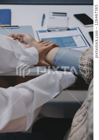 Doctor using sphygmomanometer with stethoscope checking blood pressure to a patient in the hospital. 126467365