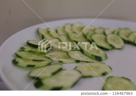 sliced cucumbers rotating on black plate, centered with strong reflection  126467963