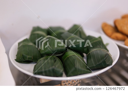 Banana leaf wrapper rotating on isolated white Fresh crabs neatly bundled in banana leaves, displayed for sale at a local market, highlighting traditional seafood preparation. 126467972
