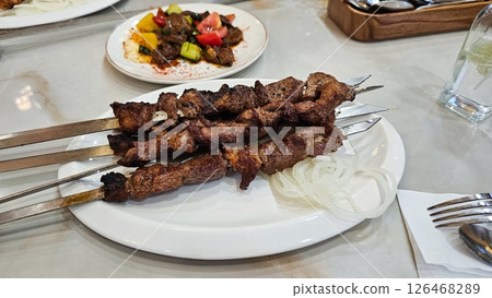 Delicious Grilled Meat Skewers with Salad and Onion Rings on a White Plate, Restaurant Delicious Grilled Meat Skewers with Salad and Onion Rings on a White Plate, Restaurant 126468289