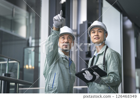 Two men in work clothes - Image of building maintenance, construction management, inspection, and investigation Two men in work clothes - Image of building maintenance, construction management, inspection, and investigation 126468349