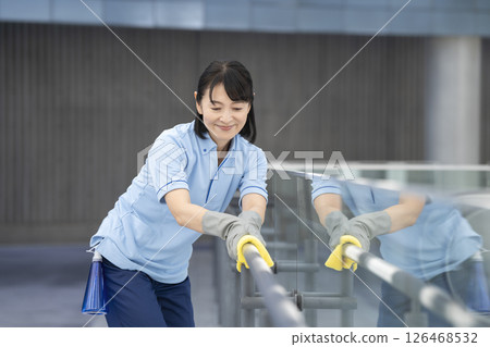 大樓清潔圖：一名 50 多歲的女性清潔人員正在擦拭走廊的扶手 126468532