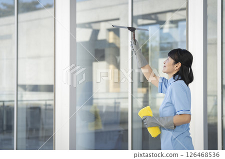 A female cleaning staff member in her 50s cleaning windows 126468536