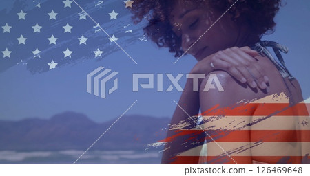 Woman on beach with American flag image over mountains and ocean background Woman on beach with American flag image over mountains and ocean background 126469648