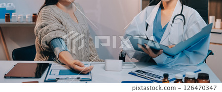 Doctor using sphygmomanometer with stethoscope checking blood pressure to a patient in the hospital. 126470347