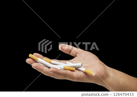 Human hand holding cigarettes, rolled tobacco in paper with a filter tube, with a black background. Concept of no or quit smoking, a bad habit, and unhealthy Human hand holding cigarettes, rolled tobacco in paper with a filter tube, with a black background. Concept of no or quit smoking, a bad habit, and unhealthy 126470433