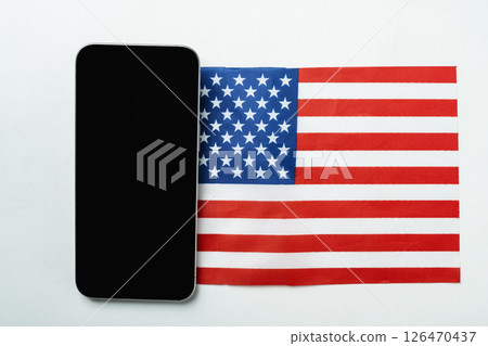The flags of the USA or the United States of America and a cellphone with a blank screen on a white background. Mockup or copy space 126470437