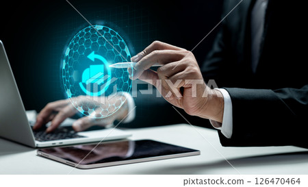 Businessman using a laptop and showing a cargo truck icon on the tablet screen. Laptop on the desk. Technology innovation on the virtual screen. Concept of industry, transport, and logistics Businessman using a laptop and showing a cargo truck icon on the tablet screen. Laptop on the desk. Technology innovation on the virtual screen. Concept of industry, transport, and logistics 126470464