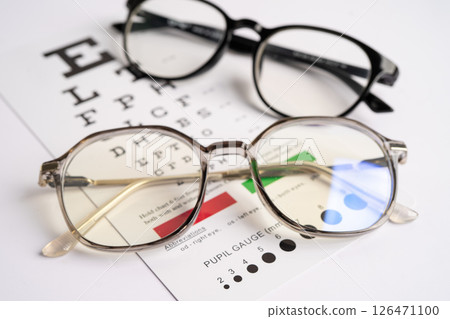 Glasses on eye testing exam chart to check eyesight accuracy of reading. 126471100