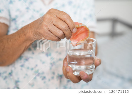 Asian senior woman patient holding and washing denture in water cleanser glass for good chewing. 126471115