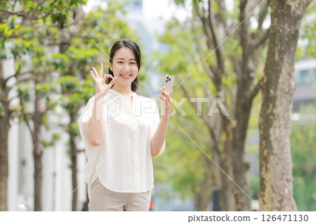 A woman looking at a smartphone outside A woman looking at a smartphone outside 126471130