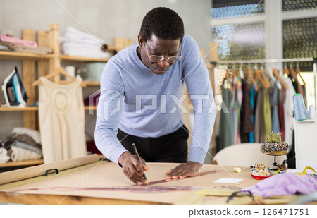 African American man tailor draw dress pattern of product on paper African American man tailor draw dress pattern of product on paper 126471751