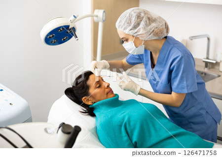 Woman cosmetician giving face injections of botulinum toxin for young woman Woman cosmetician giving face injections of botulinum toxin for young woman 126471758