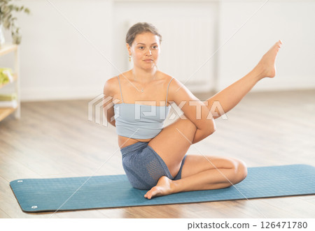 Lover of active lifestyle on yoga mat perform doing eka padahastasana salamba navasan in gym 126471780