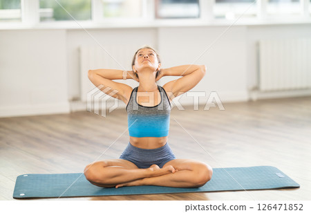 Calm young woman doing neck stretching in Padmasana pose 126471852