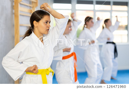 Teenage girl in kimono practicing punches and blocks during martial arts training Teenage girl in kimono practicing punches and blocks during martial arts training 126471960